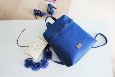 On the white wooden table blue leather bag
